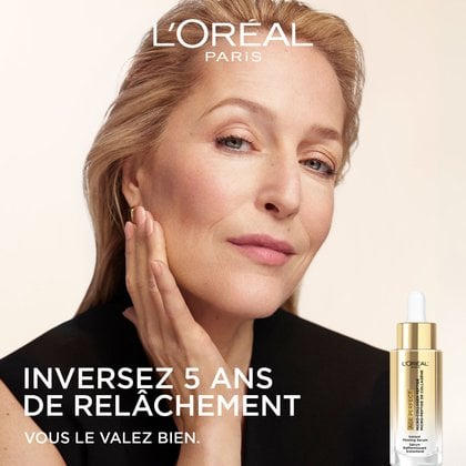 Portrait de l'ambassadrice Gillian Anderson regardant vers le haut avec assurance, sa main posée sur son cou. Le texte indique : « INVERSER 5 ANS DE RELÂCHEMENT. PARCE QUE VOUS LE VALEZ BIEN. » Un petit flacon de produit est représenté dans le coin inférieur droit.